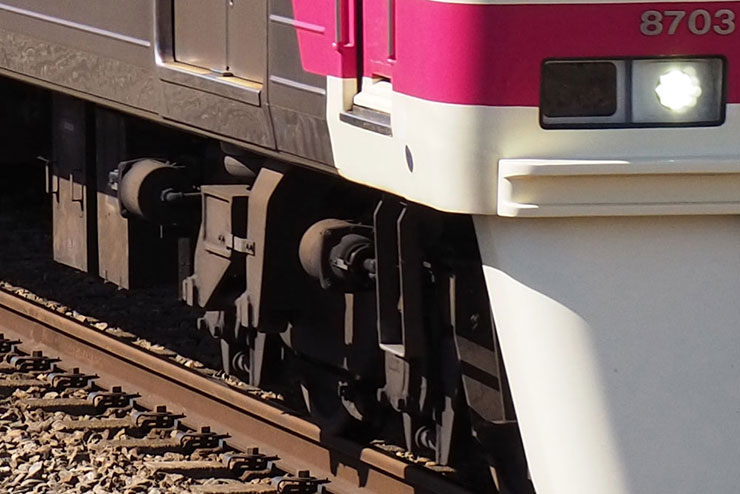 OLYMPUS M.ZUIKO DIGITAL ED 40-150mm F4.0-5.6 Rで撮影した建物の前を走る京王線の電車の画像（拡大後）