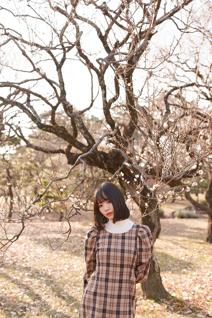SONY α1・40mmで撮影で撮影した花咲く木の前に立つ女性の画像