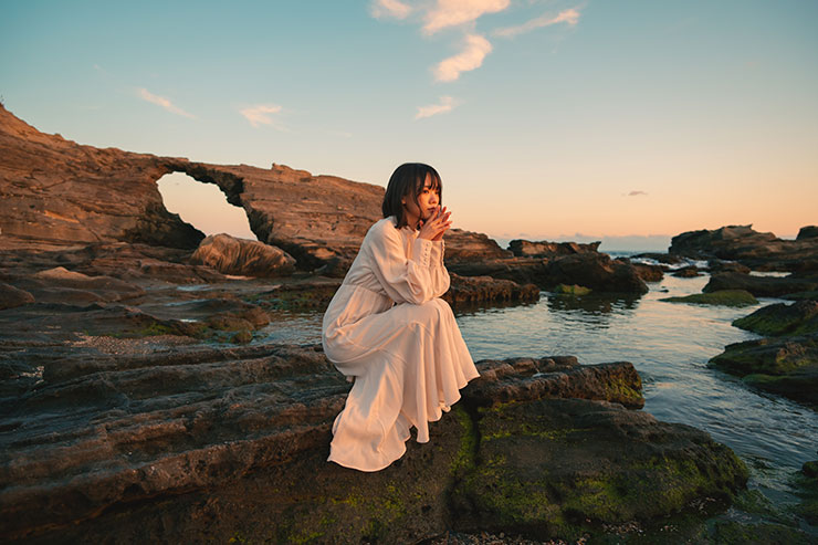 SONY α1・20mmで撮影で撮影した海岸の岩の上でしゃがむ女性の画像