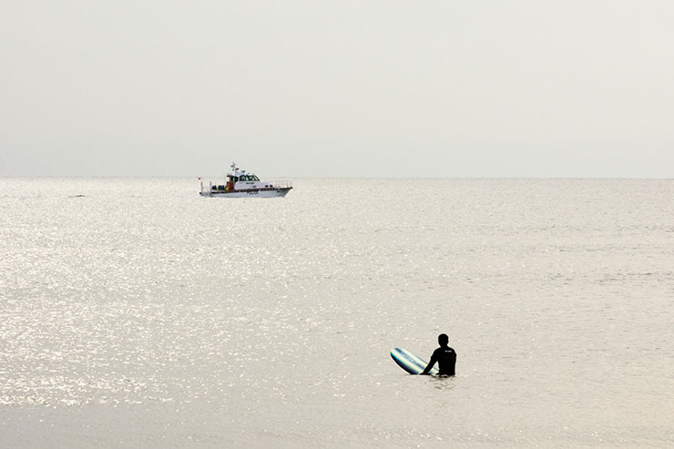 キヤノン EOS R10・RF-S18-150mm F3.5-6.3 IS STM（138mm）で撮影した海に浮かぶ船とサーファーの画像