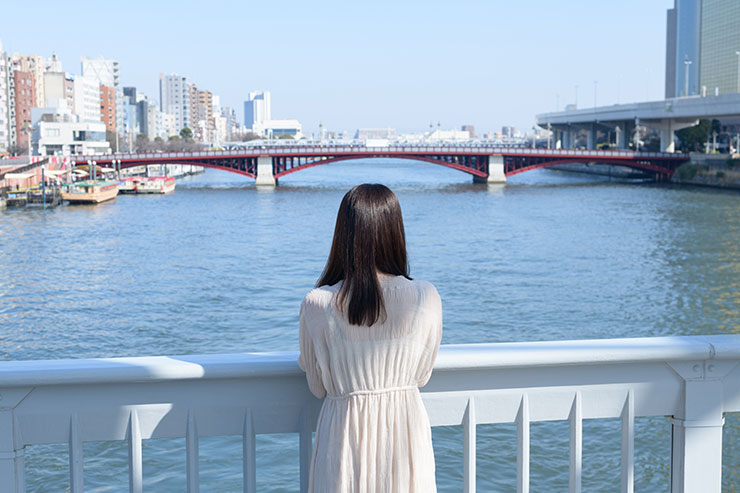 ニコン D850・AF-S NIKKOR 50mm f/1.4Gで撮影した橋から川を眺める女性の後ろ姿の画像