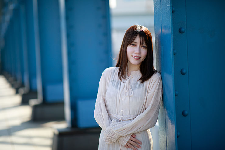 キヤノン EOS 5D MarkⅣ・EF85mm F1.4L IS USMで撮影した橋の柱に寄りかかる笑顔の女性の画像
