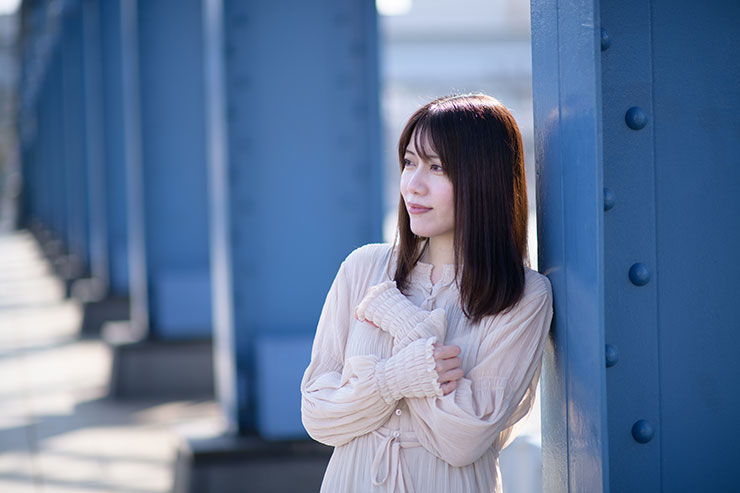 ニコン D850・AF-S NIKKOR 85mm f/1.4Gで撮影した橋の柱に寄りかかる女性の画像