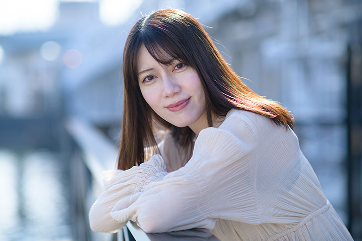 ニコン D850・AF-S NIKKOR 85mm f/1.4Gで撮影した橋の欄干にもたれる女性の画像