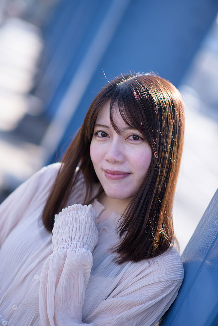 ニコン D810・AF-S NIKKOR 85mm f/1.4Gで撮影した橋の柱の前で微笑む女性の画像