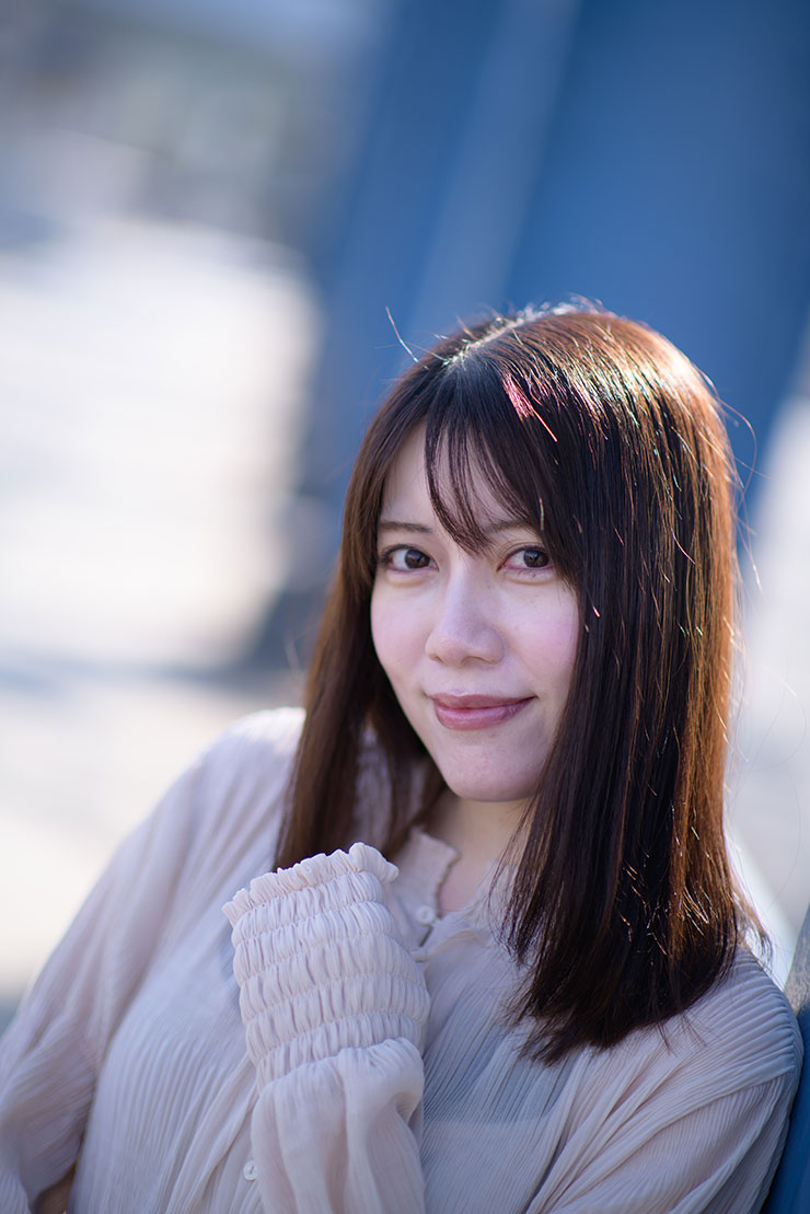 ニコン D810・AF-S NIKKOR 85mm f/1.4Gで撮影した橋の柱の前で微笑む女性の画像