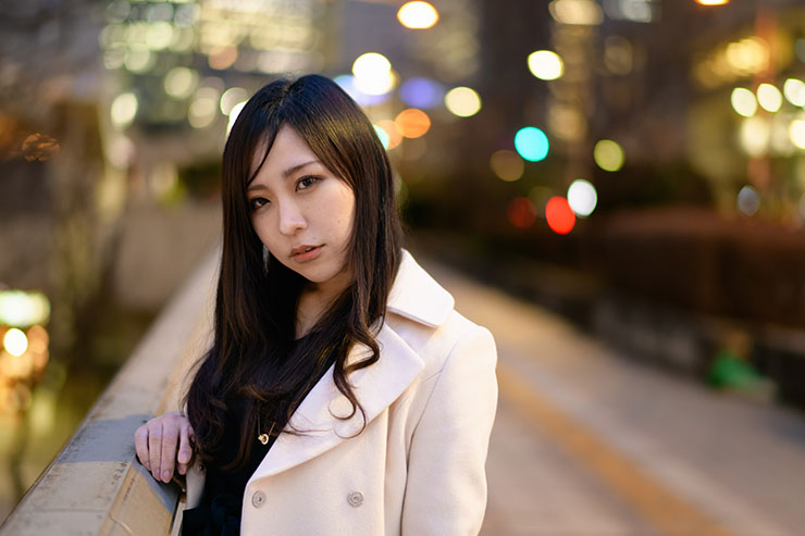 ニコン D850・AF-S NIKKOR 58mm f/1.4Gで撮影した夜の街の橋の欄干に手を置く女性の画像