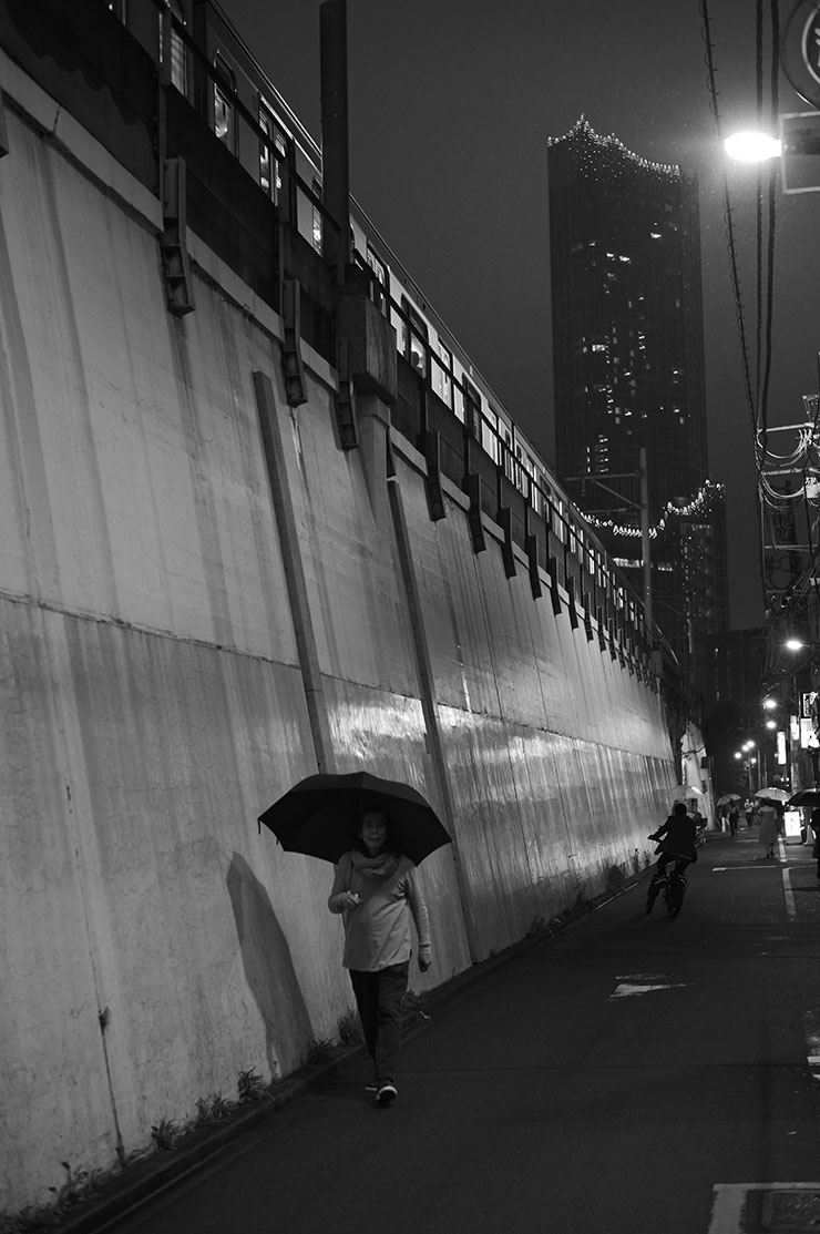 ライカM11モノクローム・ズミルックス M f1.4/50mm ASPH.で撮影した線路沿いを傘をさして歩く人々の画像