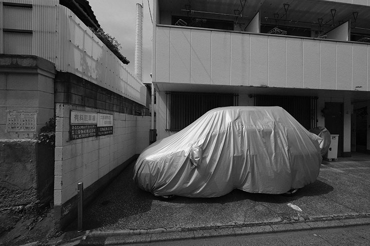 FUJIFILM X-S20・XF8mmF3.5 R WRで撮影した車が駐車しているアパートと煙突の風景画像