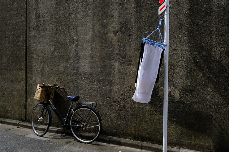 FUJIFILM X-S20・XF18mmF2 Rで撮影した道端の自転車と標識に掛けられた洗濯物の画像