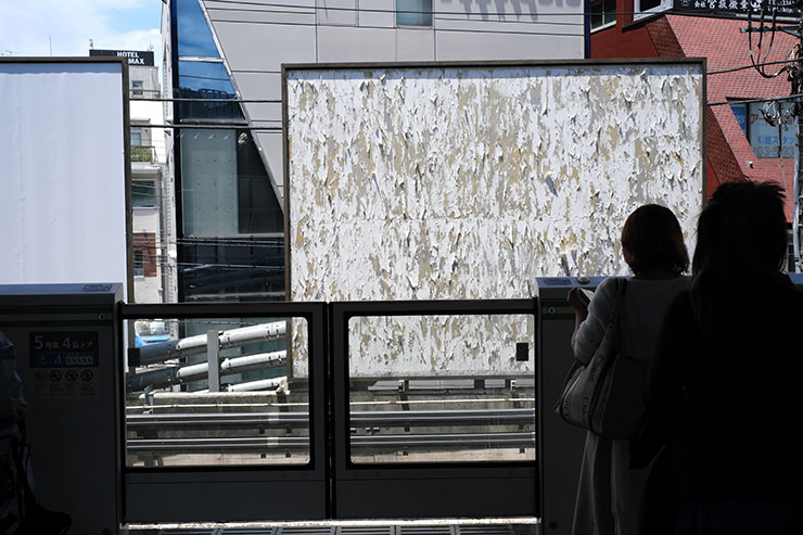 FUJIFILM  X-E4・Voigtlander ULTRON27mm F2 X-mountで撮影した駅のホームから見えるビルや空き看板の画像