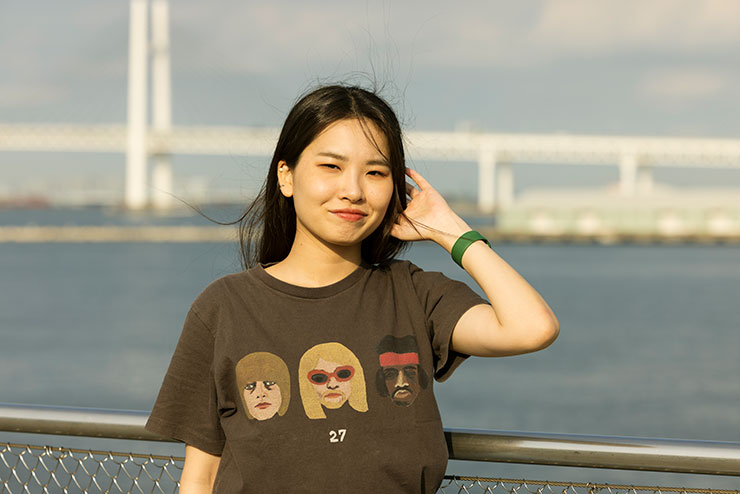 海沿いのフェンスの前でポーズをとる女性の画像