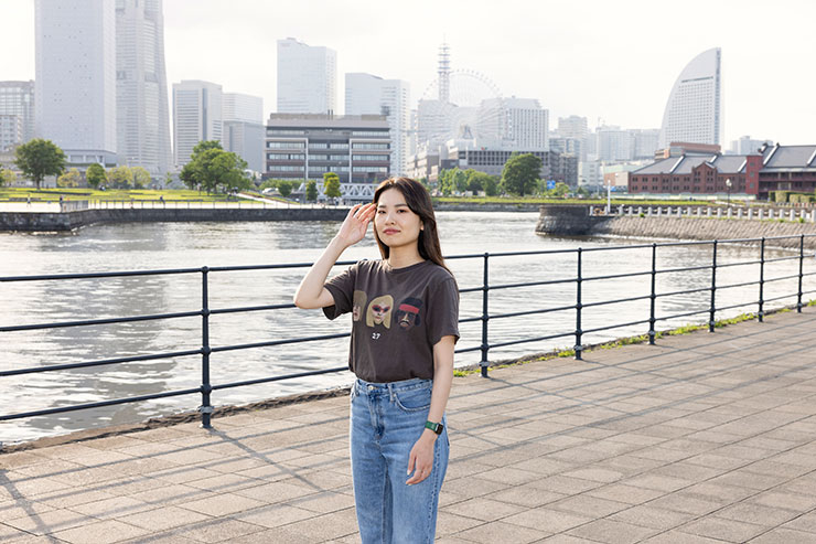 ストロボありで撮影したビルや川を背景にポーズをとる女性の画像