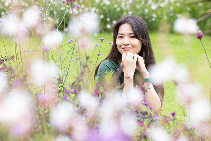 花に囲まれて座っている女性の画像
