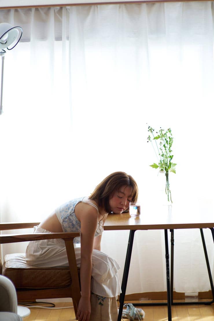 Voigtländer PORTRAIT HELIAR 75mm F1.8作例：花瓶の置かれた机に顔を預け力を抜いた女性