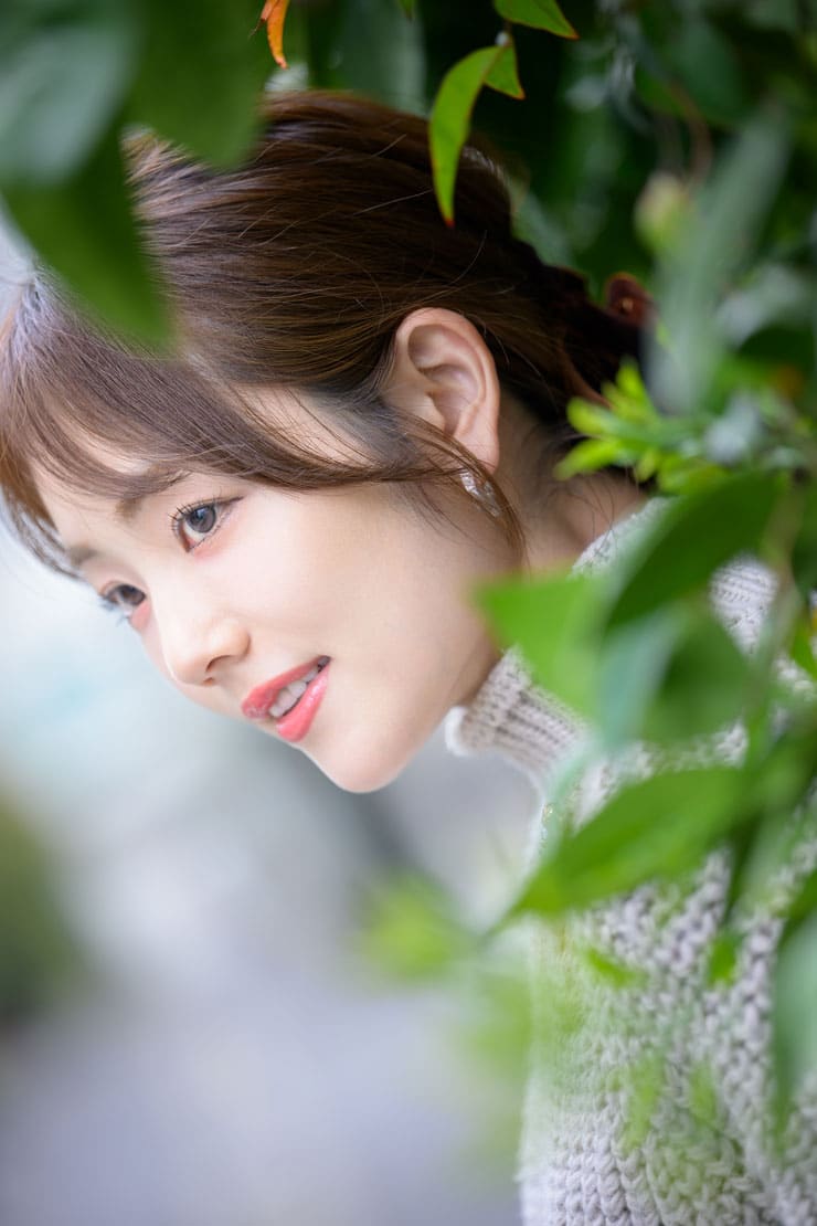 Nikon NIKKOR Z 70-200mm f/2.8 VR S II作例：植物の奥に立つ女性の顔のアップ
