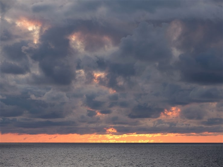 水平線と雲の間に見える夕日